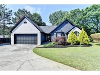 Charming single-story home featuring a brick facade, black trim, landscaped yard, and a driveway leading to a two-car garage at 2190 Ashley Crossing Ct, Lawrenceville, GA 30043