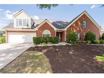 Charming brick two-story home with manicured lawn, mature trees, and attached garage, perfect for suburban living at 3027 Biltmore Woods Dr, Buford, GA 30519