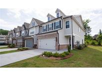New construction townhome exterior with brick accents, attached garage, landscaping, and neutral color palette at 668 Isom Walk, Suwanee, GA 30024