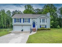 Charming two-story home with blue shutters, a two-car garage and a well-maintained front lawn at 1565 Wynfield Dr, Auburn, GA 30011