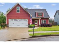 Charming two-story home features a two-car garage, landscaped yard, and patriotic American flag at 161 Overlook Cir, Canton, GA 30115
