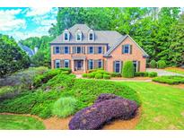 Charming two-story brick home with manicured landscaping, lush green lawn, and mature trees at 2111 Broadfield Run, Duluth, GA 30097