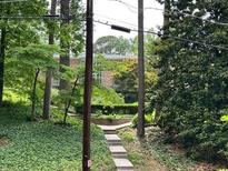 An exterior view of a multi-story home surrounded by mature trees and landscaping at 1233 Woodland Ne Ave # 5, Atlanta, GA 30324