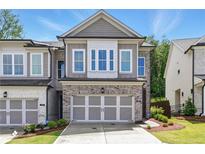 Charming two-story townhome featuring a brick facade, two-car garage, and well-manicured lawn in a desirable neighborhood at 116 Birch Tree Way, Cumming, GA 30040