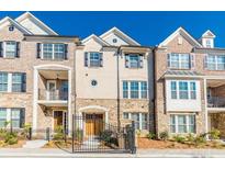 Beautiful townhouse showcasing a blend of brick and stone accents, framed by a dark metal fence and lush landscaping at 1435 Druid Manor, Atlanta, GA 30329