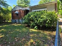 View of house with brick and siding, overgrown bushes, and a partly cloudy sky at 25 Candler Se Rd, Atlanta, GA 30317