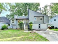 Charming gray home featuring a two-car garage, beautiful landscaping, and a welcoming front entrance at 1358 Millstream Trl, Lawrenceville, GA 30044