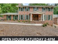 Two-story brick home with green shutters, manicured landscaping, and an inviting covered front porch at 2592 River Oak Dr, Decatur, GA 30033