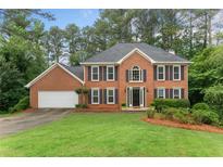 Traditional brick home with symmetrical design, well-manicured lawn, and mature trees at 739 Dushea Nw Ct, Kennesaw, GA 30144
