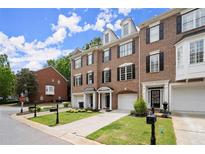 Charming brick townhomes feature manicured lawns, garages, and inviting front entrances at 2303 Waters Edge Trl, Roswell, GA 30075