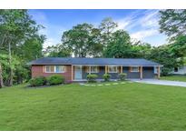 Charming single-story home with a well-maintained lawn, shrubs, and a combination brick and grey siding at 1091 Pine St, Conyers, GA 30012