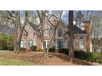 Charming brick home features a well-maintained lawn, mature trees, and architectural details at 365 Falling Creek Bnd, Duluth, GA 30097