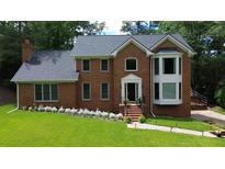 Beautiful brick two-story home featuring a manicured lawn and flowering landscape beds adding curb appeal at 10310 Amberside Ct, Roswell, GA 30076