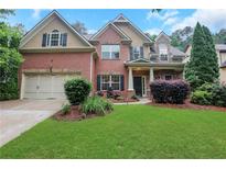 Charming two-story brick home boasts a lush lawn and manicured landscaping, offering curb appeal at 1411 Primrose Park Rd, Sugar Hill, GA 30518