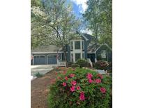 Charming two-story home with a three-car garage, landscaped yard, and blooming pink azaleas under a canopy of trees at 3017 Lana Ln, Marietta, GA 30066