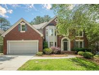 Charming brick two-story home featuring a well-manicured lawn, attached garage, and a classic arched entryway at 425 Fieldstone Lndg, Alpharetta, GA 30005