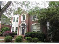 Charming two-story red brick home with a bay window, arched front door and gray shutters and a landscaped front yard at 425 Fieldstone Lndg, Alpharetta, GA 30005