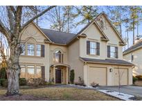 Charming tan two-story home featuring a two-car garage and a well-manicured front yard at 5105 Riverthur Pl, Duluth, GA 30096