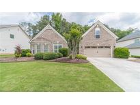 Charming brick home featuring a well-manicured lawn and an attached two-car garage at 1657 Williams Mill Way, Dacula, GA 30019