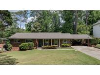 Charming brick home with well-manicured lawn, inviting curb appeal, and convenient covered parking at 1890 Silvastone Dr, Decatur, GA 30033