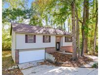 Charming split-level home with attached garage and brick facade surrounded by mature trees at 3189 Glen Hollow Dr, Rex, GA 30273