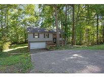 Charming split-level home with a brick and gray facade nestled amongst mature trees on a sunny day at 3189 Glen Hollow Dr, Rex, GA 30273