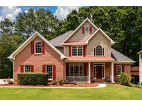 Charming brick home with manicured lawn, red shutters, and inviting front porch at 2430 Harbin Springs Cv, Dacula, GA 30019