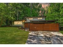 Modern house exterior featuring horizontal wood fence, carport, green lawn, and mature trees at 3539 Eaglerock Dr, Doraville, GA 30340