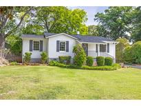 Charming exterior of home with white brick, dark shutters, front porch, and landscaped front yard at 1039 Ridgecrest Se Dr, Smyrna, GA 30080