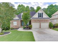 Charming home with stone facade, attached two-car garage, well-manicured lawn and inviting blue front door at 1045 Legacy Walk, Woodstock, GA 30189
