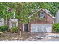 Two-story brick home featuring an attached two-car garage and a well-manicured lawn at 7078 Ravenwood Ln, Lithonia, GA 30038