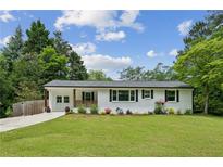 Charming renovated ranch-style home featuring a freshly painted white brick exterior and a well-manicured lawn at 1477 Spruce Se Dr, Smyrna, GA 30080