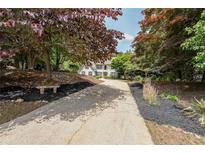 Charming two-story home featuring a welcoming driveway, lush landscaping, and a stone bench at 4135 Creekwood Dr, Cumming, GA 30041