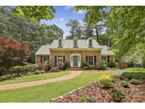 Charming brick home featuring manicured landscaping, dormer windows, and a welcoming walkway to the front door at 95 Brandon Ridge Dr, Atlanta, GA 30328