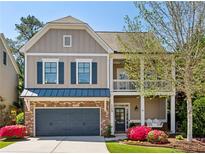 Charming two-story home with a brick-and-siding exterior, front porch swing and manicured lawn at 1749 Grand Oaks Dr, Woodstock, GA 30188