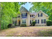 Stately two-story home featuring a symmetrical facade, black shutters, and lush, mature landscaping at 245 Ashley Forest Dr, Fayetteville, GA 30214