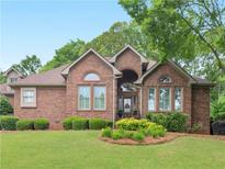 Charming brick home featuring manicured lawn, mature trees, and covered front entrance at 1466 Lake Forest Ln, Mcdonough, GA 30253