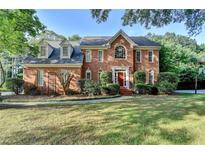 Beautiful two-story brick home with a lush green lawn and mature trees in a well-maintained neighborhood at 1885 Milfield Cir, Snellville, GA 30078