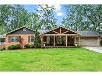 Charming brick home featuring a spacious covered porch with a gable and an attached two car garage at 3843 Lake Se Dr, Smyrna, GA 30082