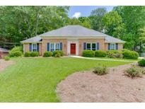 Charming brick home with a well-maintained front yard, mature trees, and colorful landscaping at 402 Johannah Sw Pl, Lilburn, GA 30047