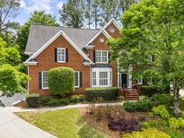 Charming two-story brick home featuring a well-manicured lawn and mature landscaping at 2425 Hamptons Psge, Alpharetta, GA 30005