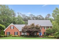 Charming two-story brick home with manicured lawn, mature trees, and blue front door at 680 Parkside Trl, Marietta, GA 30064