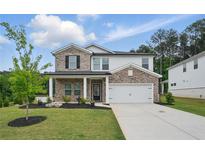 Charming two-story home with a brick and white facade, a well-manicured lawn, and an attached two-car garage at 4477 Bethany Manor Dr, Snellville, GA 30039