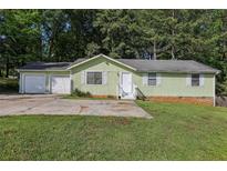 Charming single-story home with an attached two-car garage and a well-maintained front yard at 4954 Browns Mill Rd, Lithonia, GA 30038