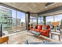 Bright living room features floor-to-ceiling windows and a comfortable red leather sofa at 943 Peachtree Ne St # 1708, Atlanta, GA 30309