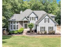 Charming two-story home with manicured lawn, stone accents, and gray siding nestled among lush trees at 3860 Overlake Dr, Cumming, GA 30041