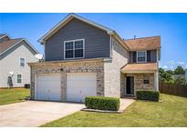 Two-story home featuring a two-car garage, brick facade, and well-maintained lawn, perfect for suburban living at 1932 Sawgrass Dr, Hampton, GA 30228