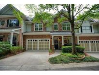 Charming townhome featuring a brick and stone facade, two-car garage, and manicured landscaping at 1203 Glenridge Ne Pl, Atlanta, GA 30342