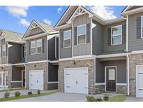 View of newly constructed townhomes with gray siding, brick accents and individual single-car garages at 229 Ivey Ter, Temple, GA 30179