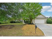 Traditional-style home featuring a two-car garage, manicured lawn, and mature landscaping at 6027 Windfall Ct, Powder Springs, GA 30127